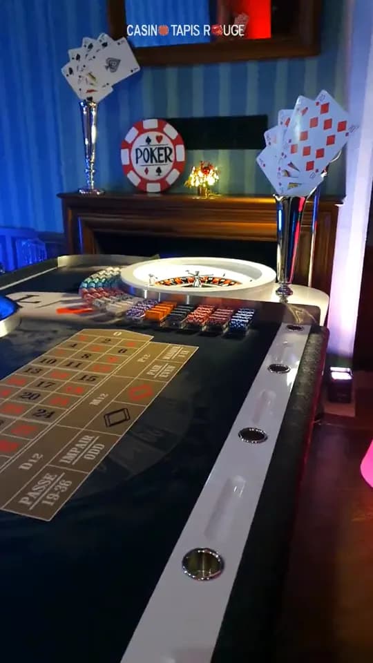 Table de roulette dans un salon aux murs bleus, avec des jetons et de grandes cartes à jouer en décor