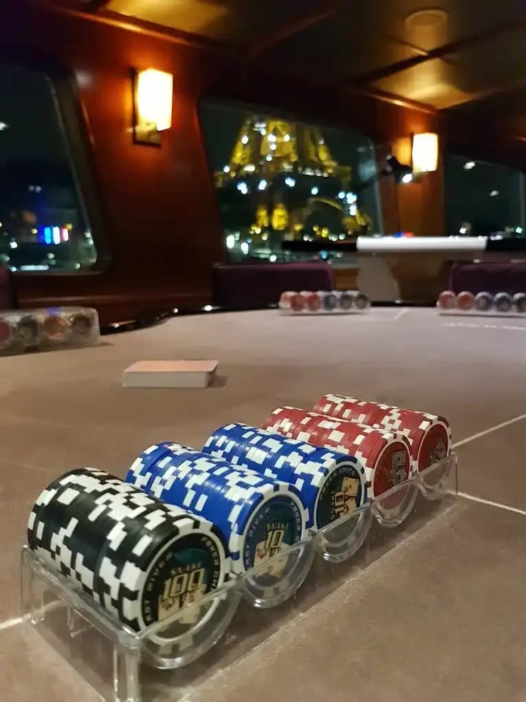 Piles de jetons sur une table, la tour Eiffel illuminée derrière la vitre