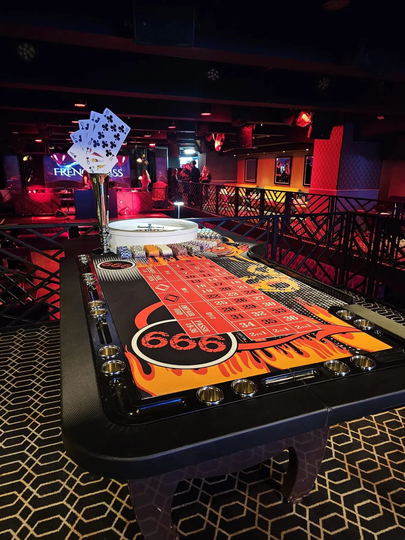 Table de roulette au décor de flammes « 666 », dans un club, avec une flûte de cartes