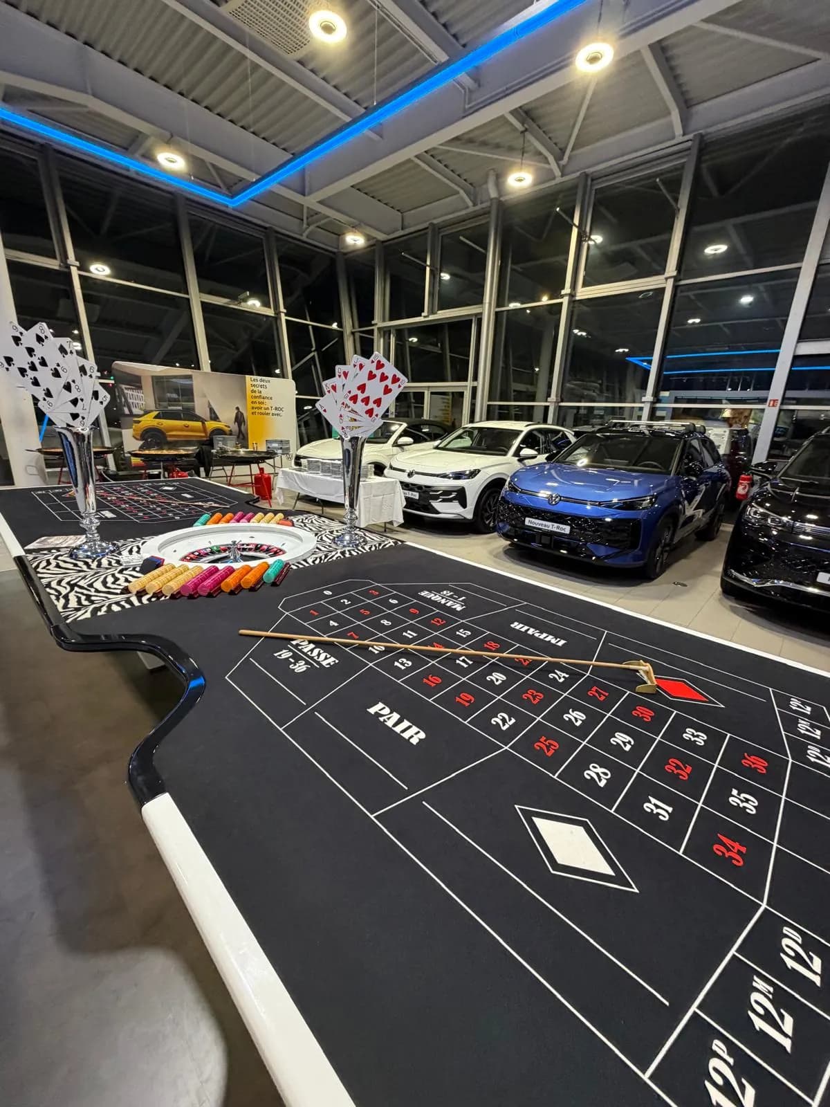 Table de roulette installée dans une concession automobile, devant les voitures exposées